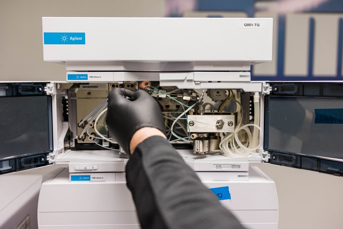A close-up of a man setting up Agilent equipment for plant testing.