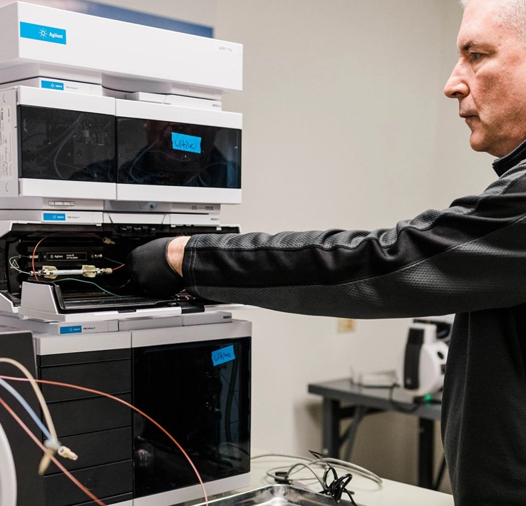 A man setting up Agilent equipment for plant testing.