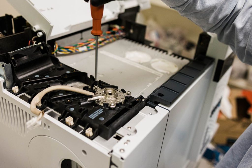 A man fixing and refurbishing an Agilent GC.