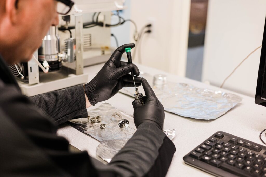 One of Aim Analytical’s technicians cleaning a part of a mass spectrometer.